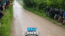 a group of people standing on the side of a muddy road with the words sky lands written on the bottom