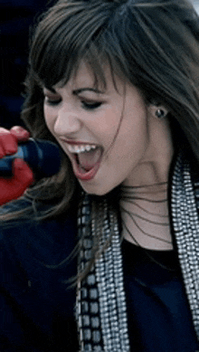 a woman is singing into a microphone with her mouth wide open