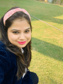 a woman wearing a pink headband smiles for a picture