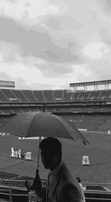 a man holding an umbrella in front of a stadium that has a sign that says ' nfl ' on it