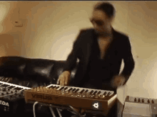 a man is playing a keyboard in a living room next to a couch .