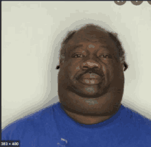 a man with a big neck and a blue shirt has 383 x 400 in the corner