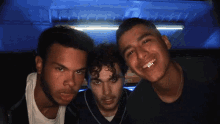 three young men are posing for a picture in a dark room with a coca cola sign in the background