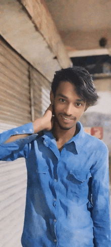 a young man in a blue shirt is smiling and looking at the camera