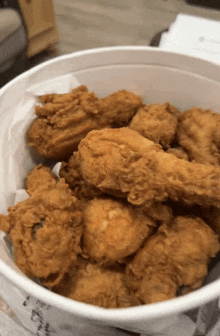 a bucket of fried chicken sits on a table next to a newspaper