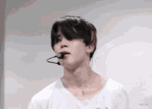 a close up of a person wearing a white shirt with a microphone in his mouth
