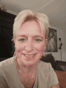 a woman wearing a necklace and earrings smiles at the camera