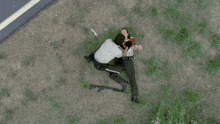 a police officer is kneeling down next to a dead man with a gun