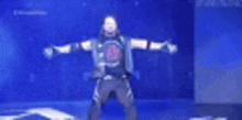 a man is standing on a stage with his arms outstretched in front of a blue background .