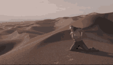 a woman is kneeling down in the desert