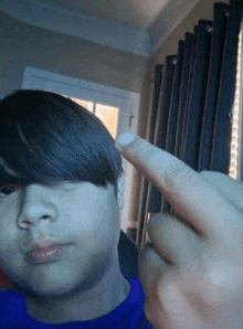 a young boy is taking a selfie with his finger on his head .