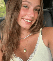 the girl is wearing a necklace and smiling for the camera .