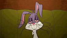 bugs bunny is laying on a green couch with his eyes closed and smiling .