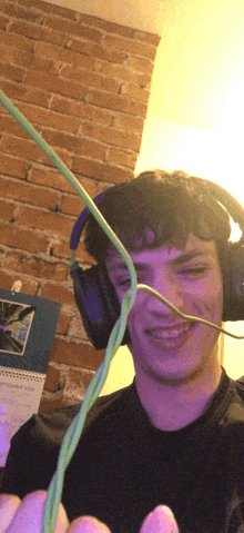 a young man wearing headphones and holding a green wire