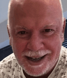 a close up of a man 's face with a beard smiling .