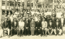 a group of people are posing for a picture in front of a wooden structure .