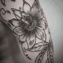 a black and white tattoo of a flower and leaves on a man 's arm