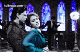 a man and a woman are dancing in a room with stained glass windows .