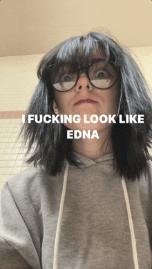 a woman wearing glasses and a grey hoodie with the words i fucking look like edna on the bottom