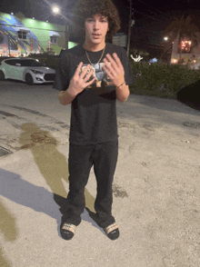 a young man with curly hair wearing a black shirt with a picture of a man on it