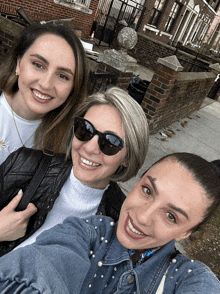 three women wearing sunglasses and pearls pose for a photo