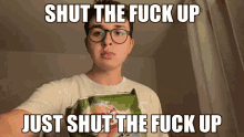 a man with glasses is holding a bag of potato chips with a caption that says " shut the fuck up just shut the fuck up "