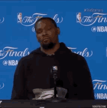 a man sitting at a table with a microphone in front of a blue background that says the finals on it