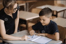 a teacher is helping a young boy with his homework in a classroom