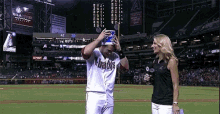 a baseball player wearing a shirt that says ' arizona ' on it is being interviewed by a female reporter