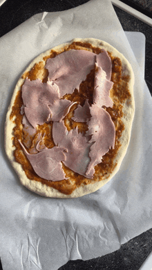 a pizza with ham on top of it on a piece of paper