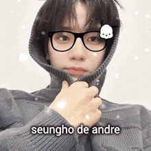 a young man wearing glasses and a sweater with the name seungho de andre written on the bottom