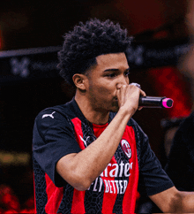 a man singing into a microphone wearing an emirates fly better shirt