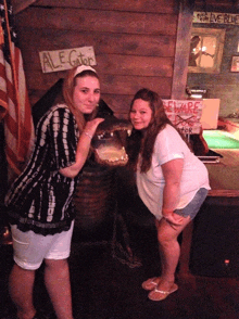 two women standing in front of an alligator with a sign that says ale gator