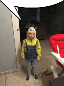 a little boy in a minion costume stands in front of a high chair