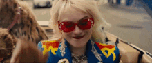 a woman wearing red sunglasses is sitting in a car next to a leopard .