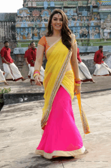 a woman wearing a yellow and pink saree is smiling