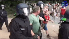 a group of police officers are holding a man in a green shirt and a boy in a red shirt .