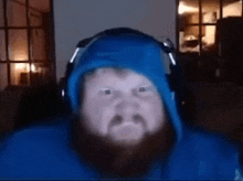 a man with a beard wearing headphones and a blue jacket .