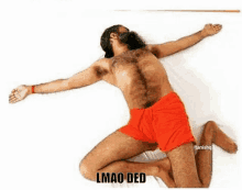 a shirtless man with a beard is laying on his stomach on a bed with his arms outstretched .