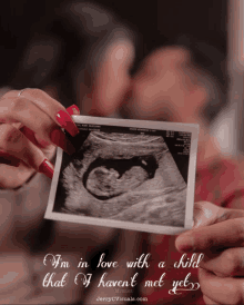 a couple holding a picture of a baby with the words i 'm in love with a child