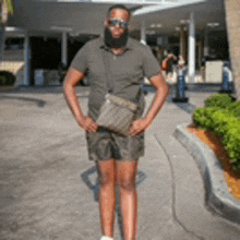 a man with a beard and shorts is standing on a sidewalk .