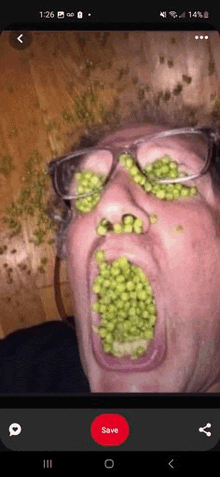 a man with peas on his face is taking a picture on his phone .