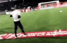 a man is running on a soccer field in front of a sign that says ' coca cola ' on it