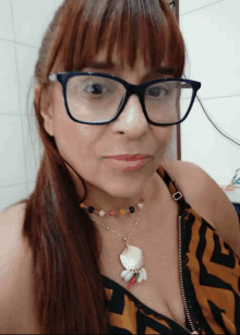 woman wearing glasses and a necklace with a shell pendant