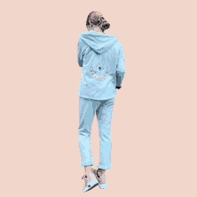 a woman wearing a light blue hoodie with a pink crescent moon on the back