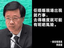 a man in a suit and tie is speaking into a microphone with chinese writing behind him