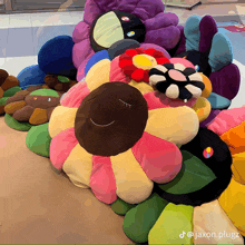 a bunch of colorful stuffed flowers are sitting on a floor