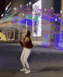 a woman is dancing in front of a building with a sign that says ' what a wonderful night ' on it