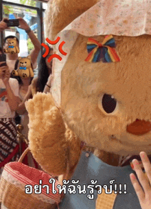 a teddy bear with a rainbow bow on its head is being photographed by a woman