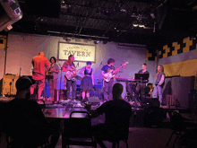 a group of people playing instruments on stage in front of a sign that says yellow cab tavern